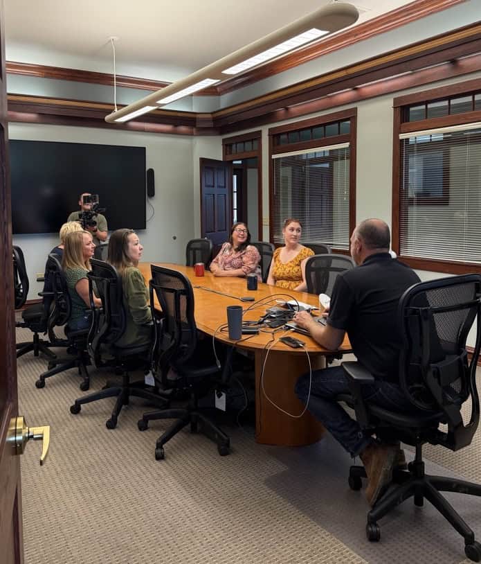 Headquarter Filming Filming at Headquarters, Office team is sitting at oval conference table with President Chris Goss