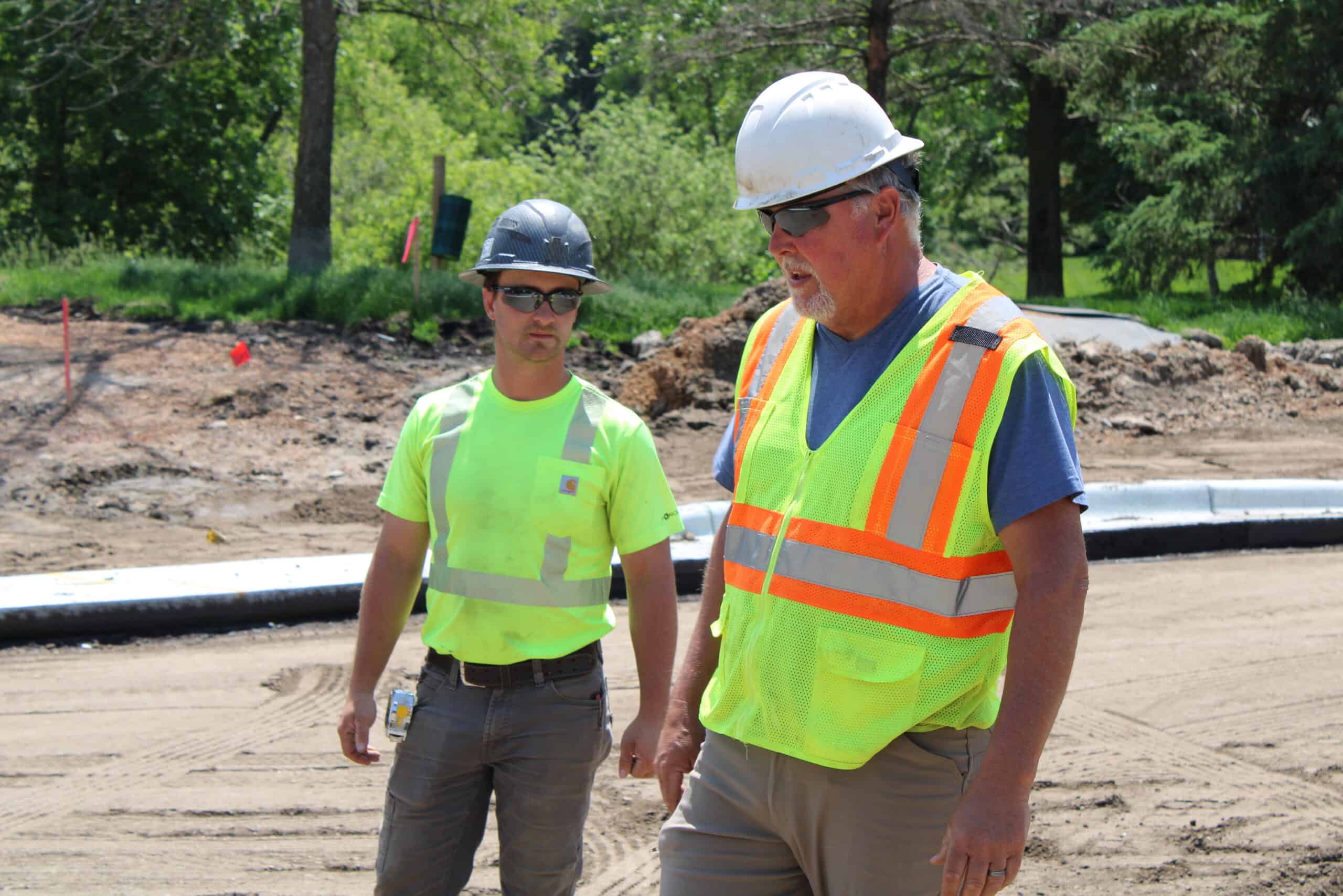CHASKA, MN HOFFMAN EMPLOYEES Two Hoffman Construction Employees On Chaska Jobsite in Safety Gear Standing Beside One Another