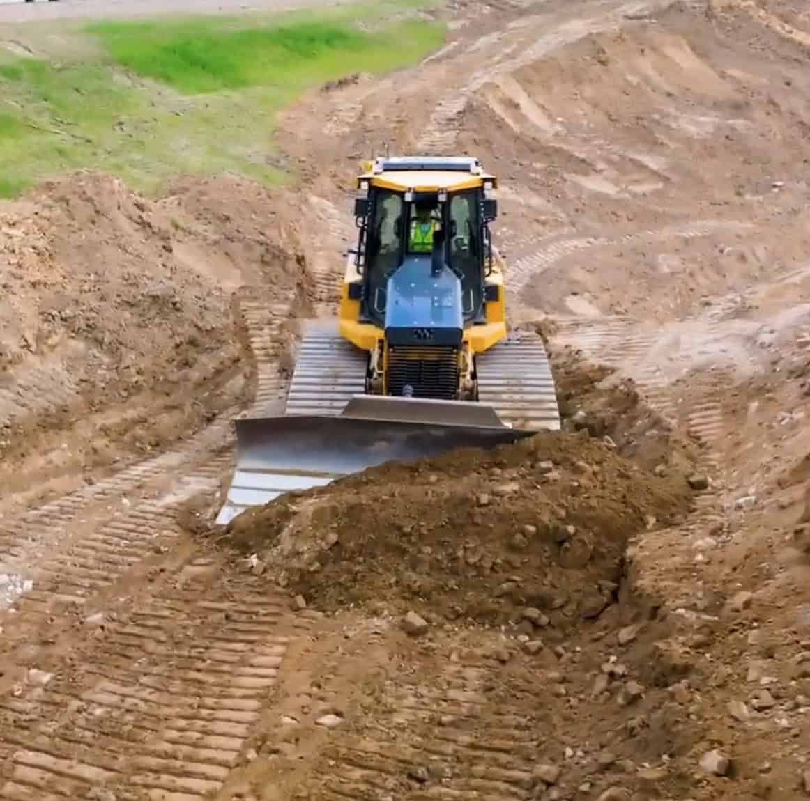A bulldozer pushes dirt up a graded hill.