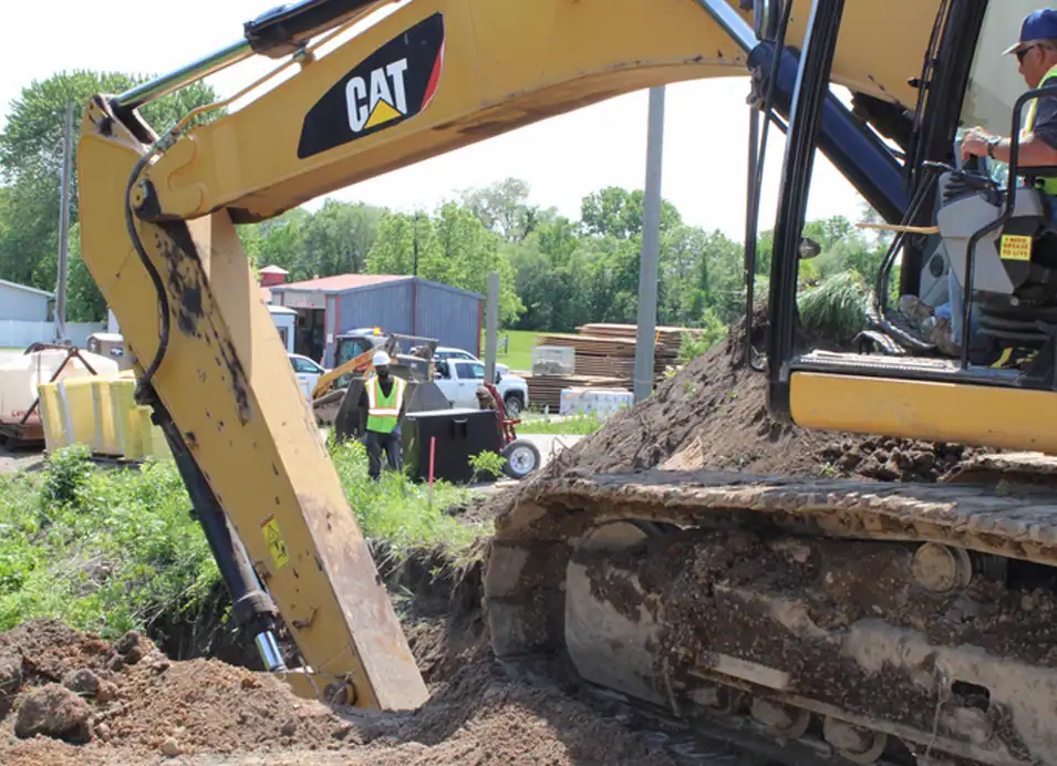 excavator-action A person operating an excavator with the shovel down deep in a trench.